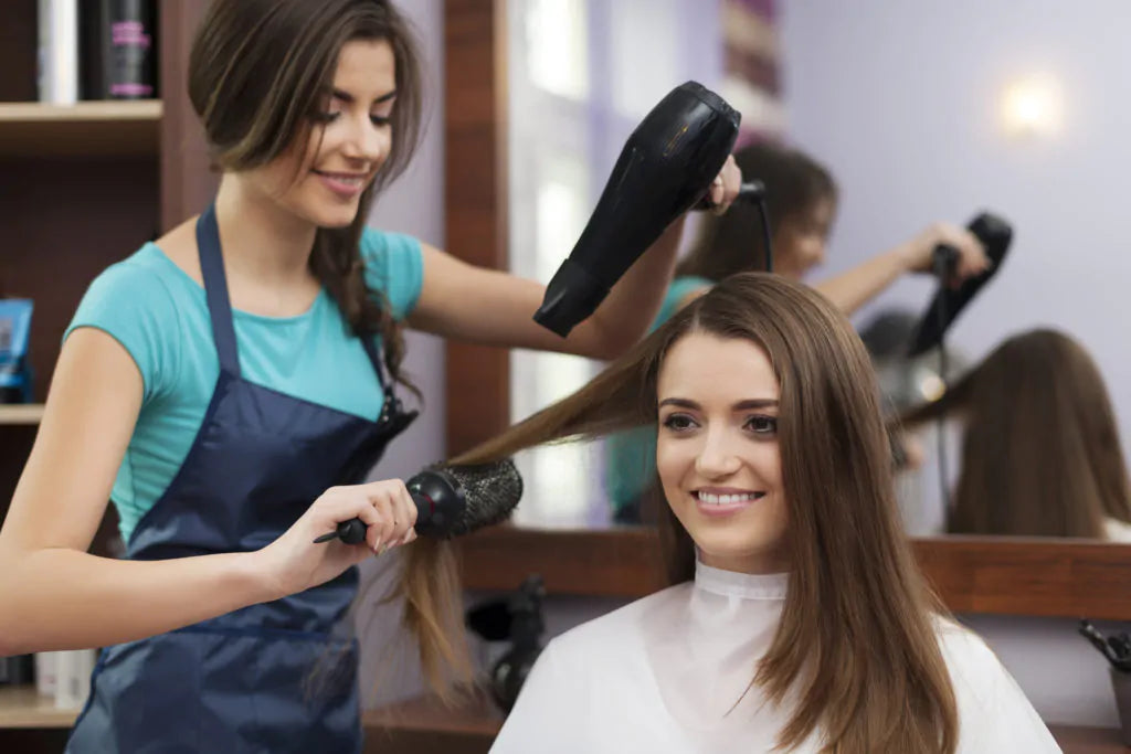 Female hairdresser using hairbrush and hair dryer