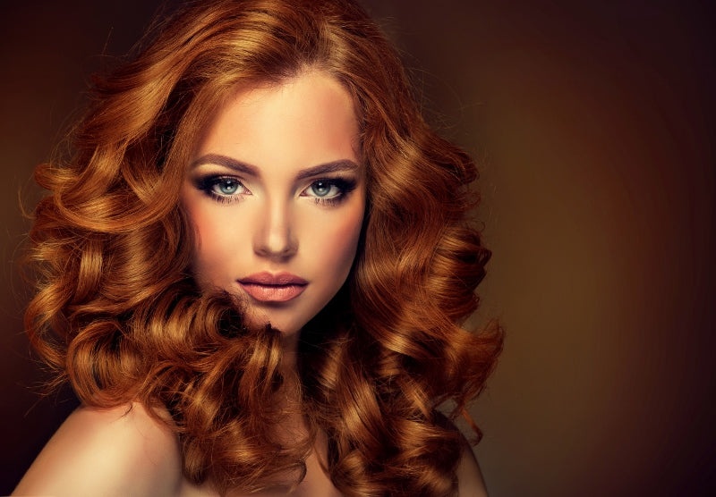 Girl model with long red wavy hair. Big curls on the red head . Hairstyle permanent waving