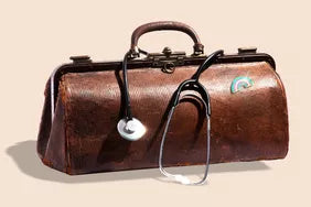 Vintage brown leather Doctor's bag with a stethoscope around the handles, and a LGBTQ+ transgender pin on the outside