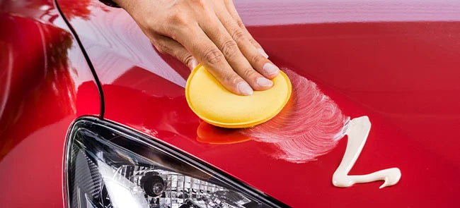 A mans hand with a watch polishing red car