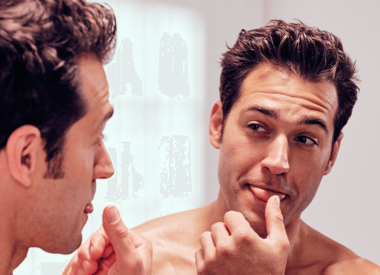 Man looking at self in mirror, about to lick his thumb.