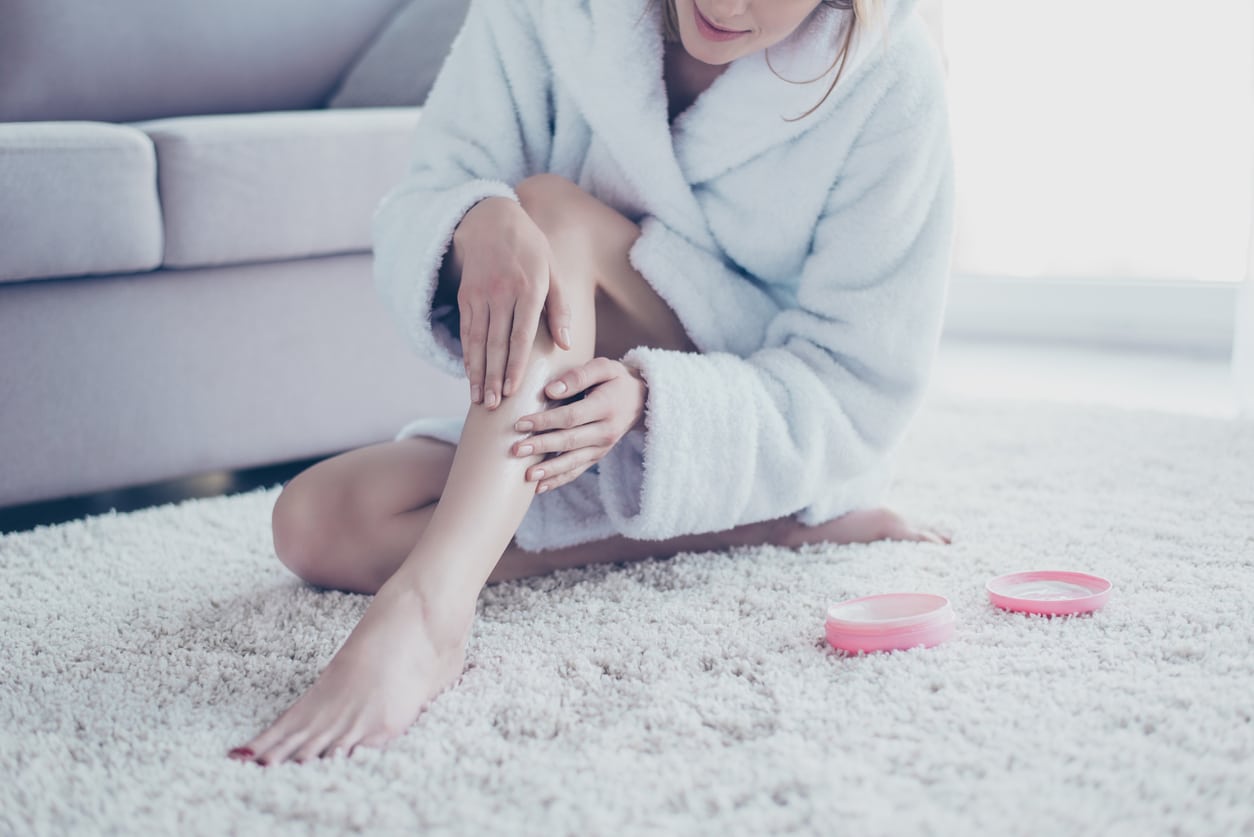 Woman putting lotion on legs