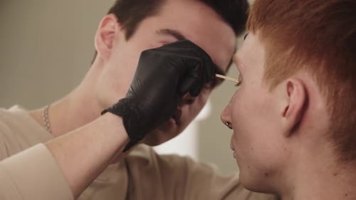 A Man Eyebrow Master Waxing the Hairs of the Eyebrow of His Client