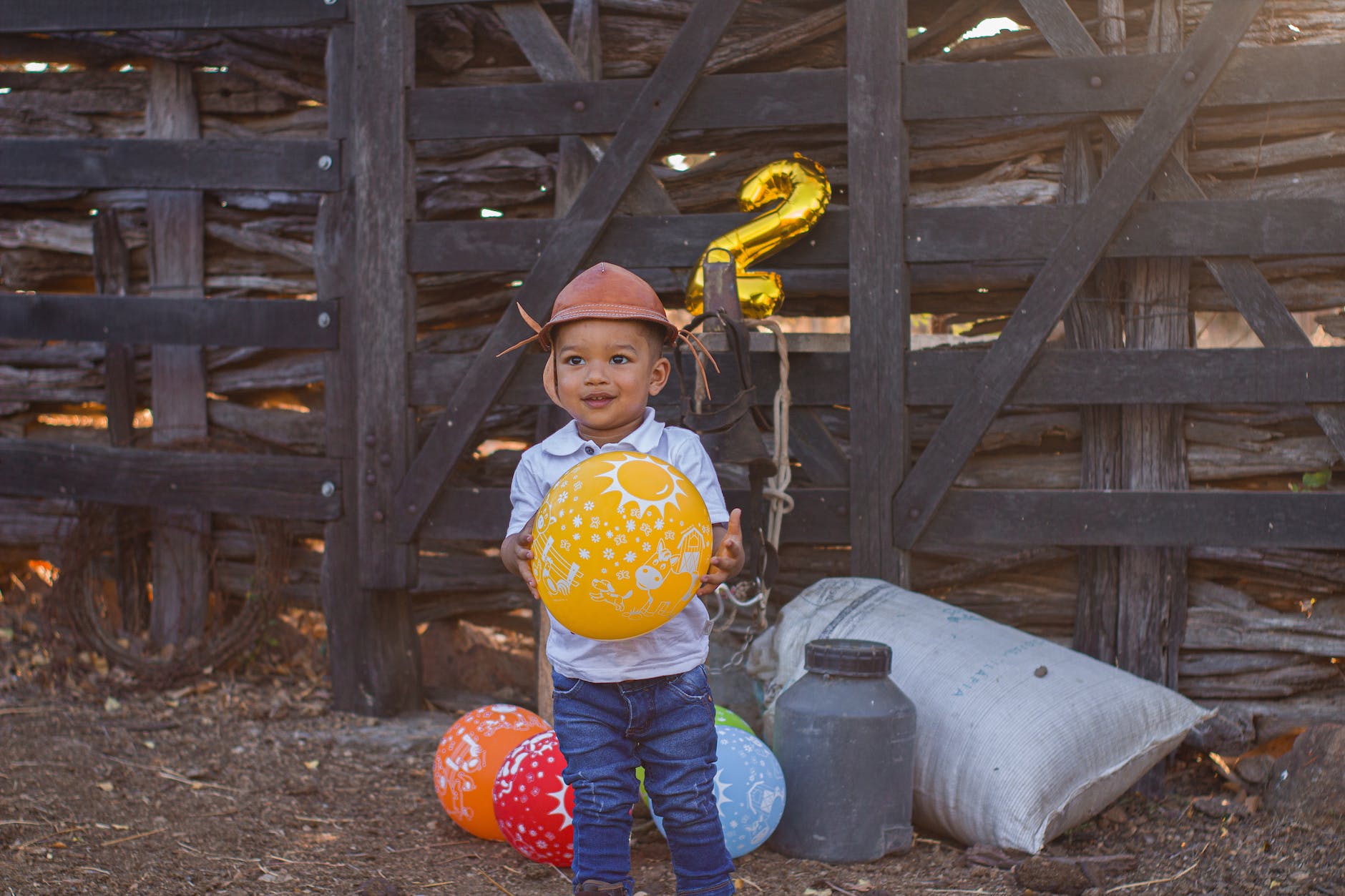 child celebrating second birthday holding balloons