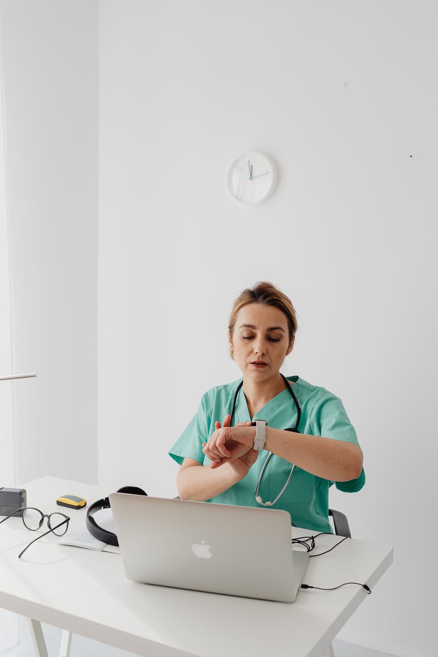 woman sitting in front of laptop looking at her watch