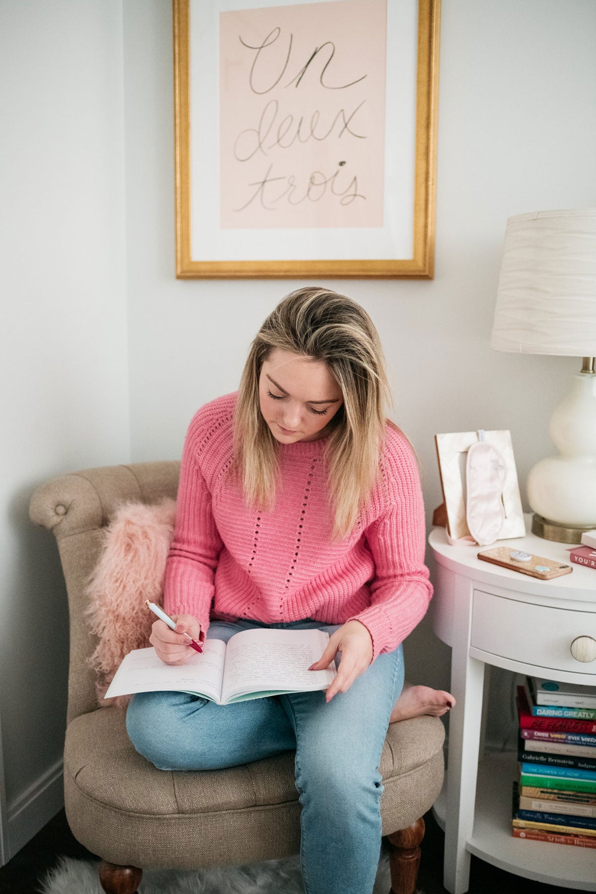 Chicago lifestyle and wellness blogger Bows & Sequins writing in a journal in her bedroom.