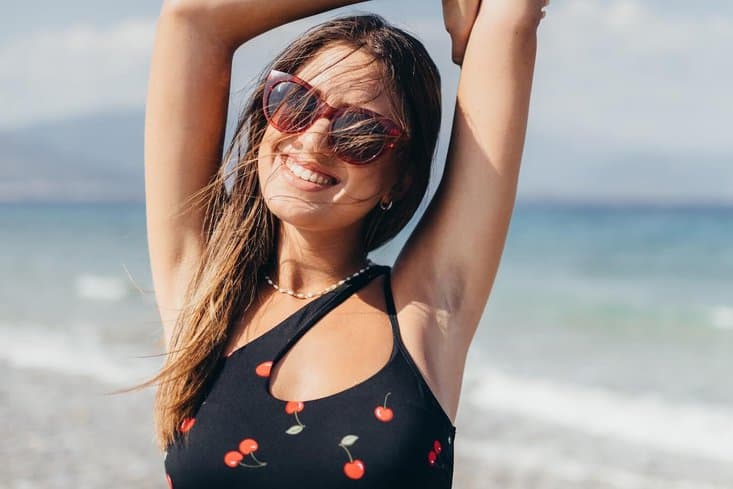 underarm hyperpigmentation on a female with arms raised at the beach